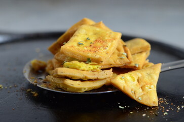 Traditional Indian snack methi mathri – crispy deep-fried savory crackers made with fenugreek leaves and spices, served as tea-time or festive snack – flaky North Indian namkeen