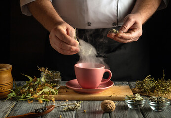 A person prepares herbal tea by steeping a tea bag in a pink cup, surrounded by herbs, wooden...