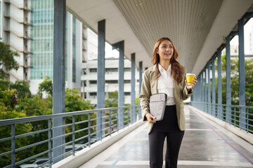 Smiling businesswoman holding takeaway coffee, commuting to work in the city.