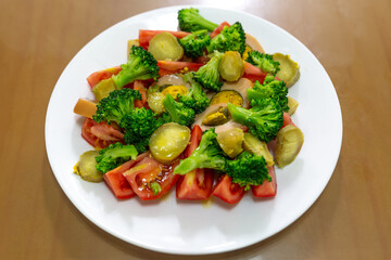 a salad plate of tomatoes, avocados, sweet potatoes, and broccoli
