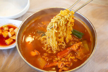 A bowl of ramen noodles with vegetables and eggs. The bowl is white and the noodles are orange