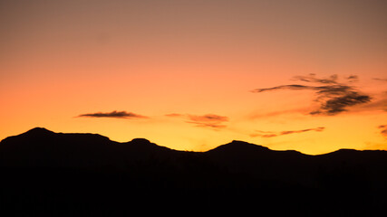 Golden sunset with mountains in silhouette on the horizon.