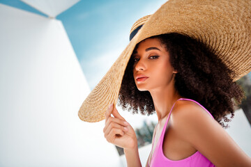 Elegant young woman in summer fashion with a wide hat enjoying an outdoor sunshine moment...