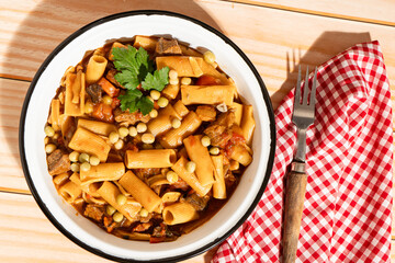Delicious pasta with beef stew, peas, and tomatoes served in rustic bowl