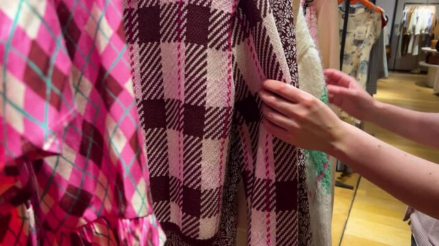 A girl walks along the rows of clothes, looking at some models to choose what she likes. Upmarket French department store Galeries Lafayette Haussmann, Paris, France.