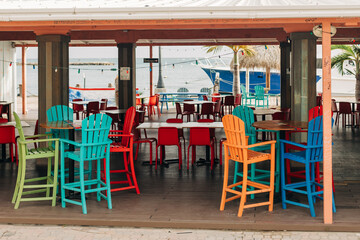 Colorful outdoor seating area by the beach with bright chairs and tables during the day