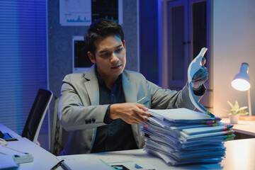 Asian businessman working late checking documents in office at night