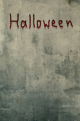 Art shabby grey plastered wall with the lettering Halloween in blood, copy space, vertical image.