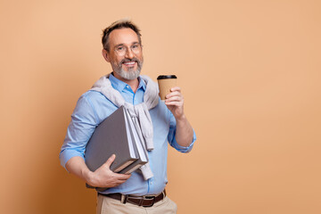 Confident mature businessman holding folders and coffee on beige background promoting lifestyle and...