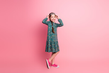 Adorable young girl posing in a vibrant dress against a pink background, expressing joy and charm...