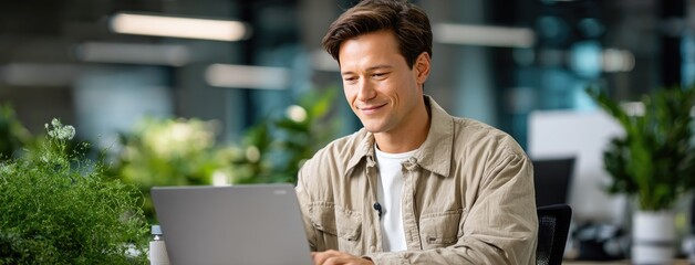 Individual actively working on laptop in an open office, utilizing a green screen designed for presenting business concepts, with room available for written content.