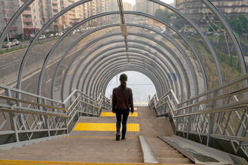 Voronezh, Russia, June 14, 2025: A girl descends the stairs in an overpass, seen from behind