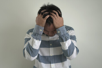 An asian unhappy and annoyed business man is suffering headache and stresses, closing his ears with...