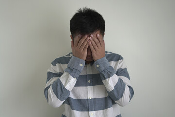 An asian unhappy and annoyed business man is suffering headache and stresses, closing his ears with...