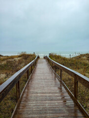 Obraz premium A pier going down to the ocean beach at Beachwalker Park on a rainy day, Kiawah Island, South Carolina
