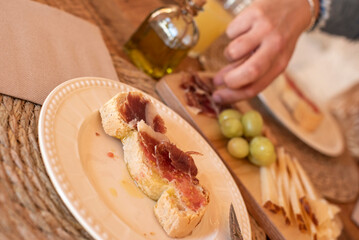 hand picking up ham for a toast with tomato and oil