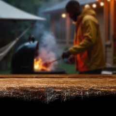 Wooden garden table with people at barbecue grill and garden in background – outdoor cooking...