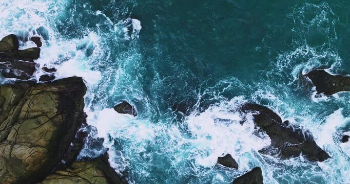 Top down aerial view from above of big waves crashing and foaming on rock stones,Amazing seashore nature background,Wide angle view ocean sea from drone camera 4k High quality footage ProRes 422