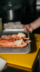 A person is holding a plate of food with a crab on it. The plate is on a yellow cutting board