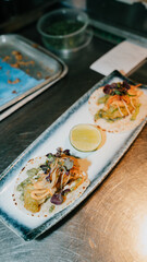 A plate of food with two tacos and a lime on it. The plate is on a counter and the food looks delicious