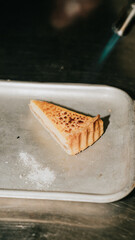 A slice of pie is on a silver tray. The pie is golden brown and has a crust