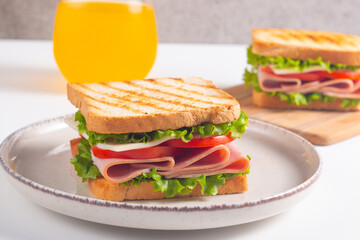 Close-up of two sandwiches with bacon, salami, prosciutto and fresh vegetables on rustic wooden...