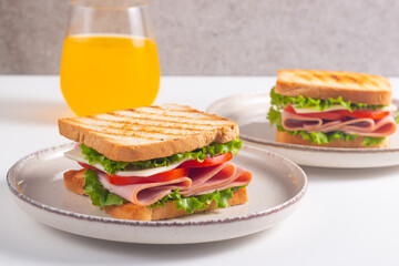 Close-up of two sandwiches with bacon, salami, prosciutto and fresh vegetables on rustic wooden...