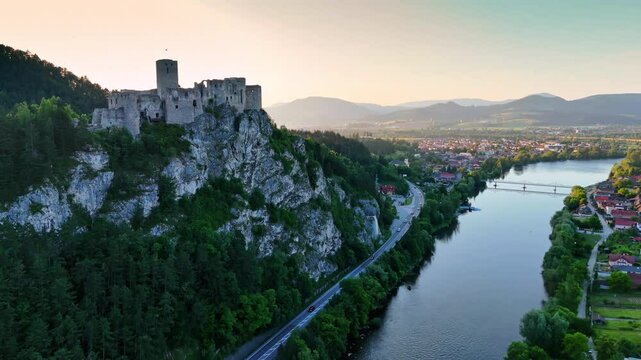Big medieval-like castle on the picturesque mountain. River flows at the foot of the mountain. Aerial perspective on the beautiful countryside. Slovakia.