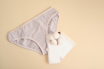 women's comfortable panties, pad and cotton flower, feminine hygiene products made of natural materials concept close up beige background