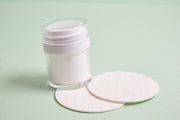 reusable skin care pads and white mock up bottle with pump dispenser for cosmetics on green background, pastel shades