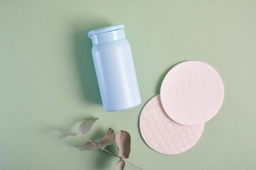 reusable skin care pads and blue mock up cosmetic bottle on green background, pastel shades