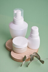 various white bottles on pastel green background, cosmetic containers stand on wooden heart-shaped tray, natural products and self-care