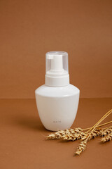 wheat and white bottle for product with dispenser on brown background, mock up container for cosmetics or detergent, natural product