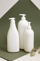 eucalyptus and three different white bottles without labels, containers for liquid soap or shampoo with dispenser,, mock up natural cosmetics product