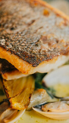 A fish fillet with a side of vegetables is served on a plate. The dish is garnished with parsley and has a light, fresh appearance