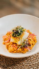 A plate of food with a fish on top of it. The fish is surrounded by vegetables and a sauce