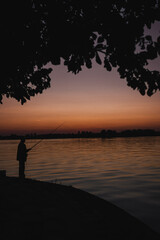 Fototapeta premium A breathtaking red sunset over a tranquil lake, capturing the serene beauty of nature at dusk. The vibrant hues of crimson, orange, and gold reflect off the still water, creating a mirror-like surface