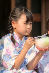 縁側でかき氷を食べる浴衣姿の姉妹