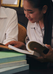 Two of Diversity Student study and reading book together in library at asian college. Happy multi ethnic woman search for knowledge in classroom at university. Education concept-vertical image.