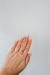 Elegant hand adorned with rings showcasing manicured nails against a simple background