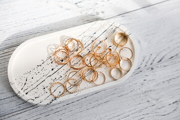 Collection of elegant gold rings displayed on a stylish tray on a wooden surface in soft light