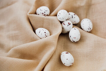 Quail eggs arranged on light fabric with speckles and natural textures in a cozy setting