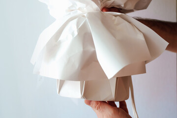 Gift box being held with white paper wrapping just before unwrapping in a cozy indoor setting