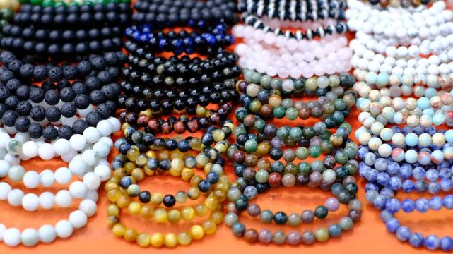 A collection of bracelets with different colors and designs. The bracelets are arranged in rows and are displayed on an orange surface