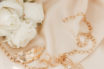 Elegant gold chain and rose arrangement on soft fabric during a romantic event preparation