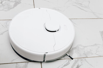 Robot vacuum cleaner operates on tiled floor during a bright afternoon in a modern home setting