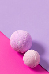 Colorful bath bombs on a pink and purple background create a playful aesthetic