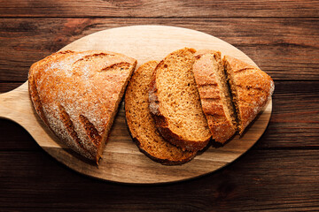 Freshly baked brown bread sliced and resting on a wooden cutting board