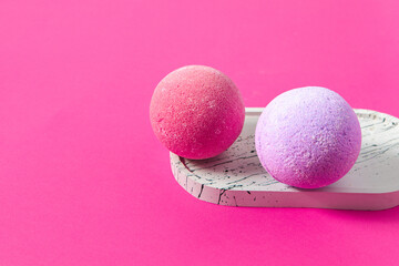 Colorful bath bombs resting on a stylish tray against a vibrant pink backdrop