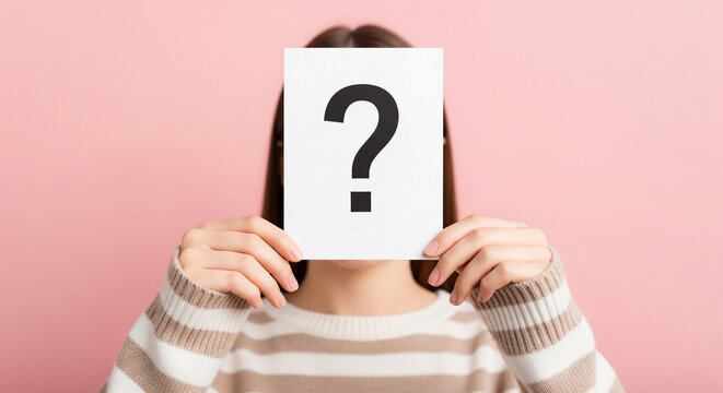 Woman holding paper with question mark obscuring face, against pink background. Illustrates anonymity, uncertainty, or question concept